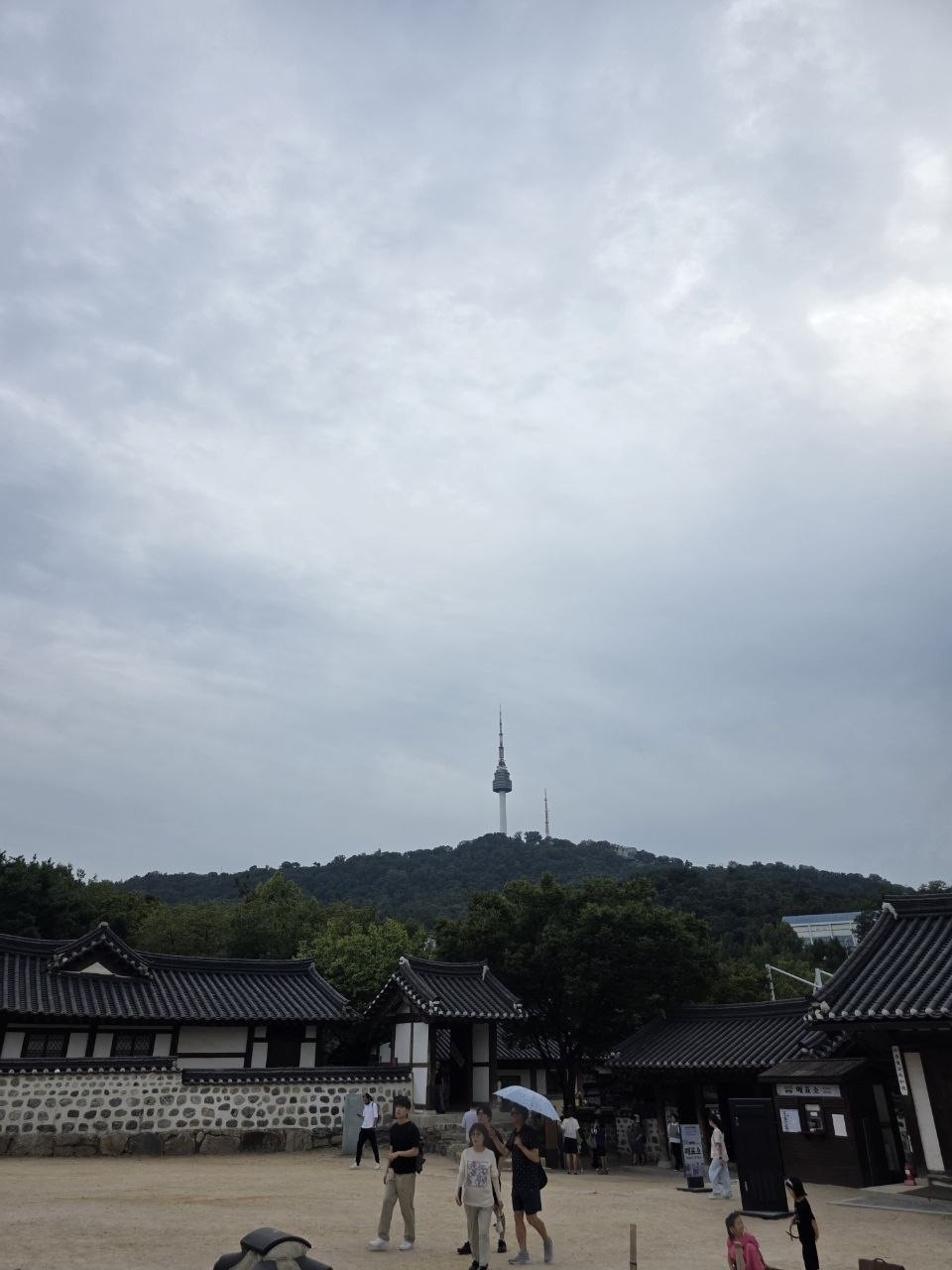 남산골한옥마을 마당 너머 한옥 지붕 위로 남산과 N서울타워가 보이는 흐린 날의 풍경