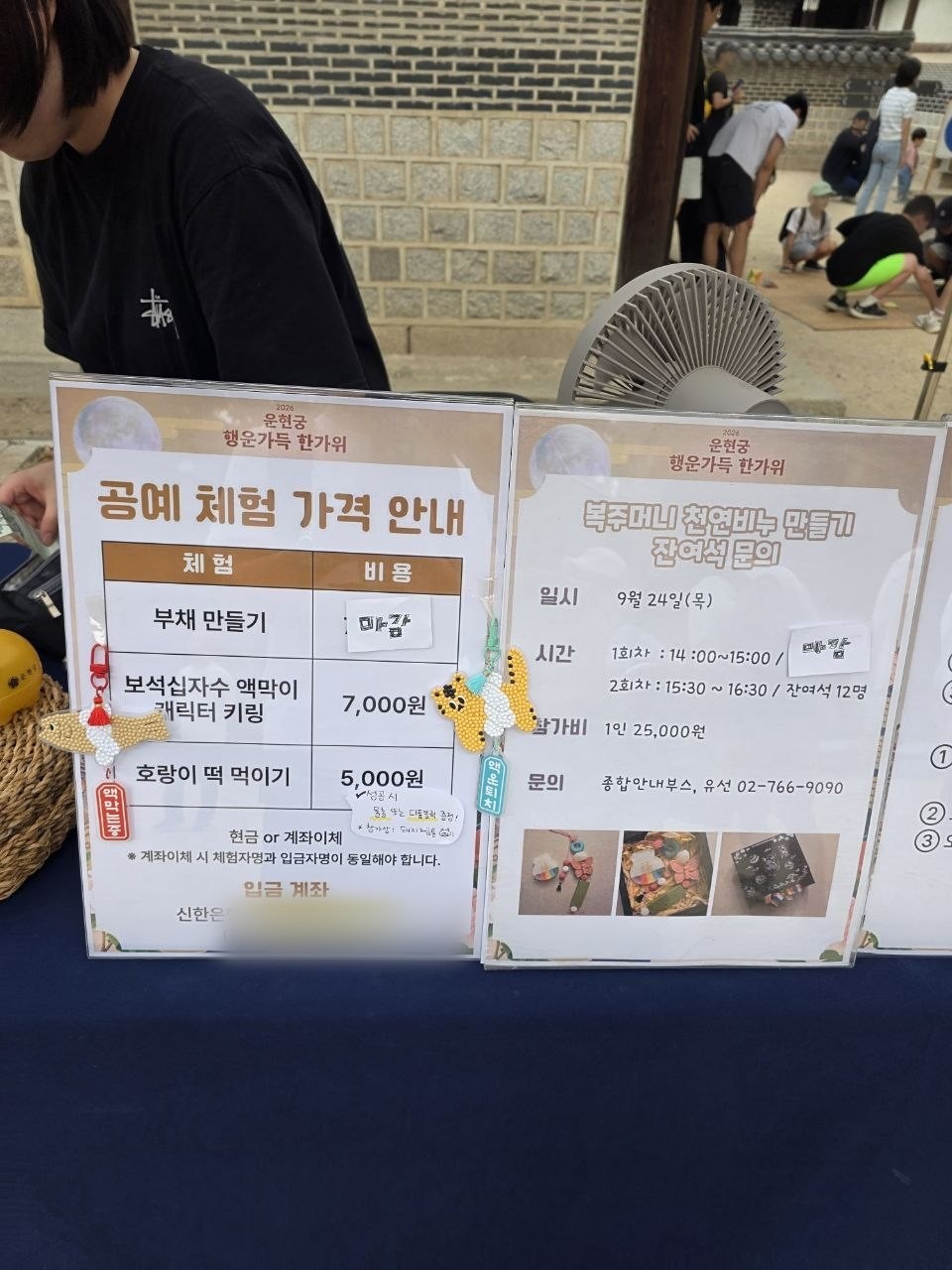 운현궁 행운가득 한가위 공예 체험 가격 안내판 — 부채 만들기 마감, 보석십자수 액막이 캐릭터 키링 7,000원, 호랑이 떡 먹이기 5,000원, 옆에 복주머니 천연비누 만들기 1인 25,000원 안내